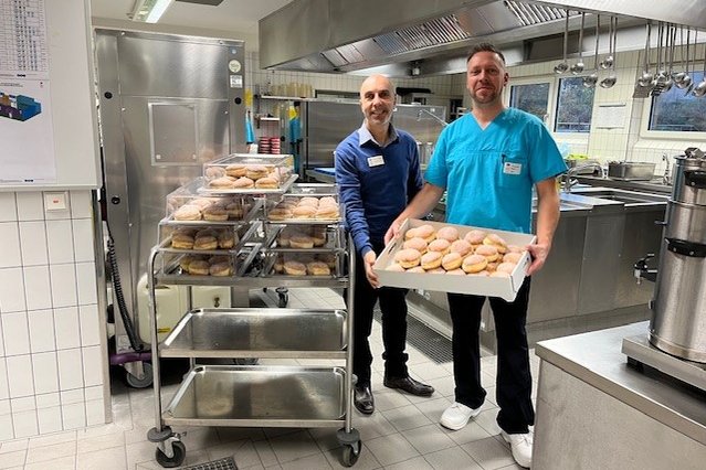 Zwei Mitarbeiter in der Küche des Seniorenzentrums Eckental mit Tablett voller Backwaren.