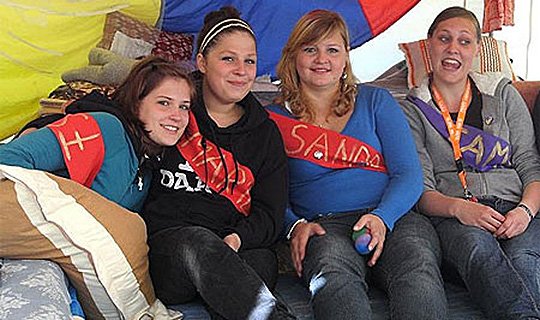 Vier junge Frauen sitzen entspannt im bunten Raum während eines Seminars.