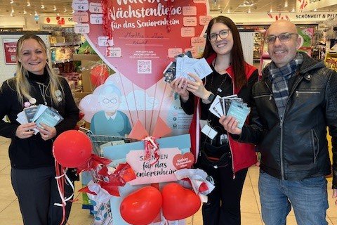 Drei Personen stehen vor einem Spendenstand im Supermarkt.