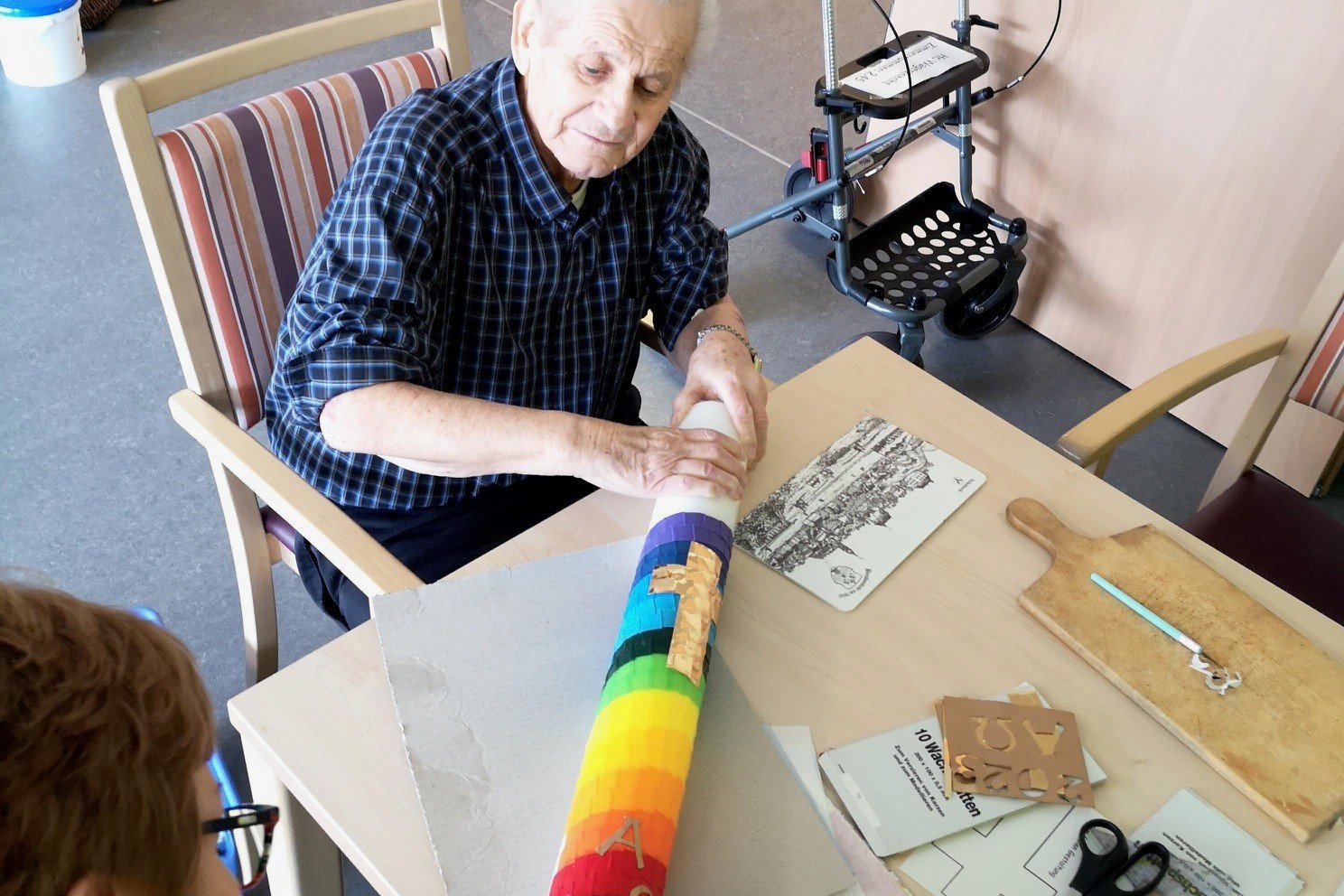 Senior dekoriert bunte Kerze im Seniorenzentrum Eckental.