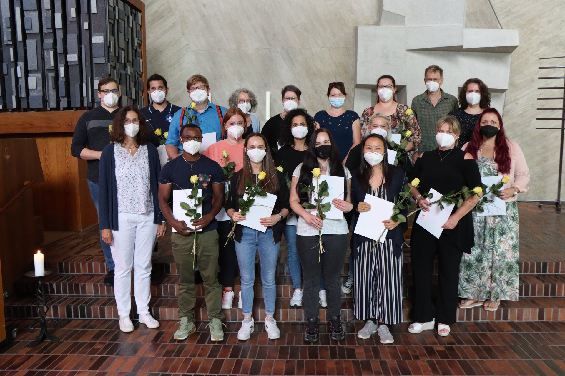 Gruppe von Menschen mit Masken und gelben Rosen bei einer Zeremonie.