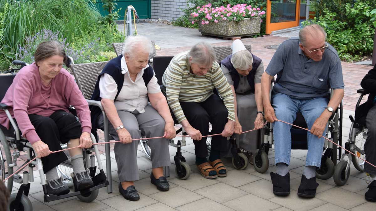 Senioren in Rollstühlen bei Bewegungsübung mit Seil im Seniorenzentrum Nürnberg.