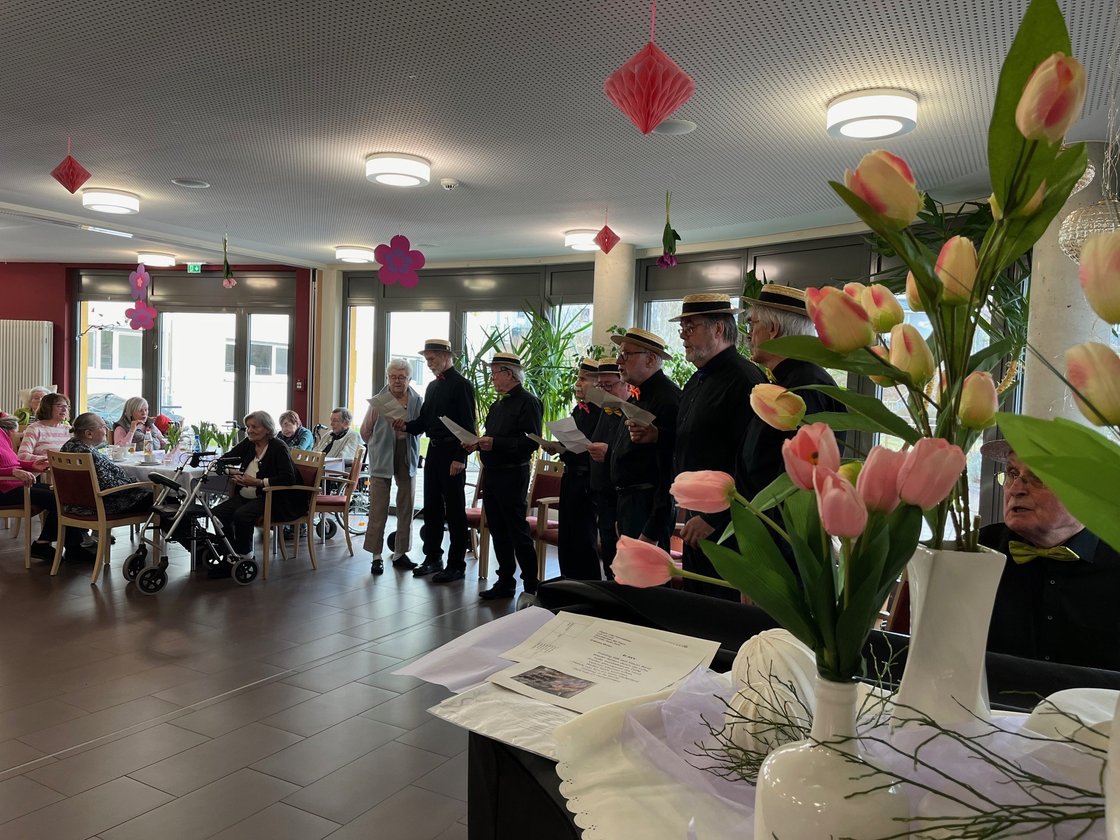 Seniorenchor singt im Seniorenzentrum Eckental, dekorierter Raum mit Tulpen.