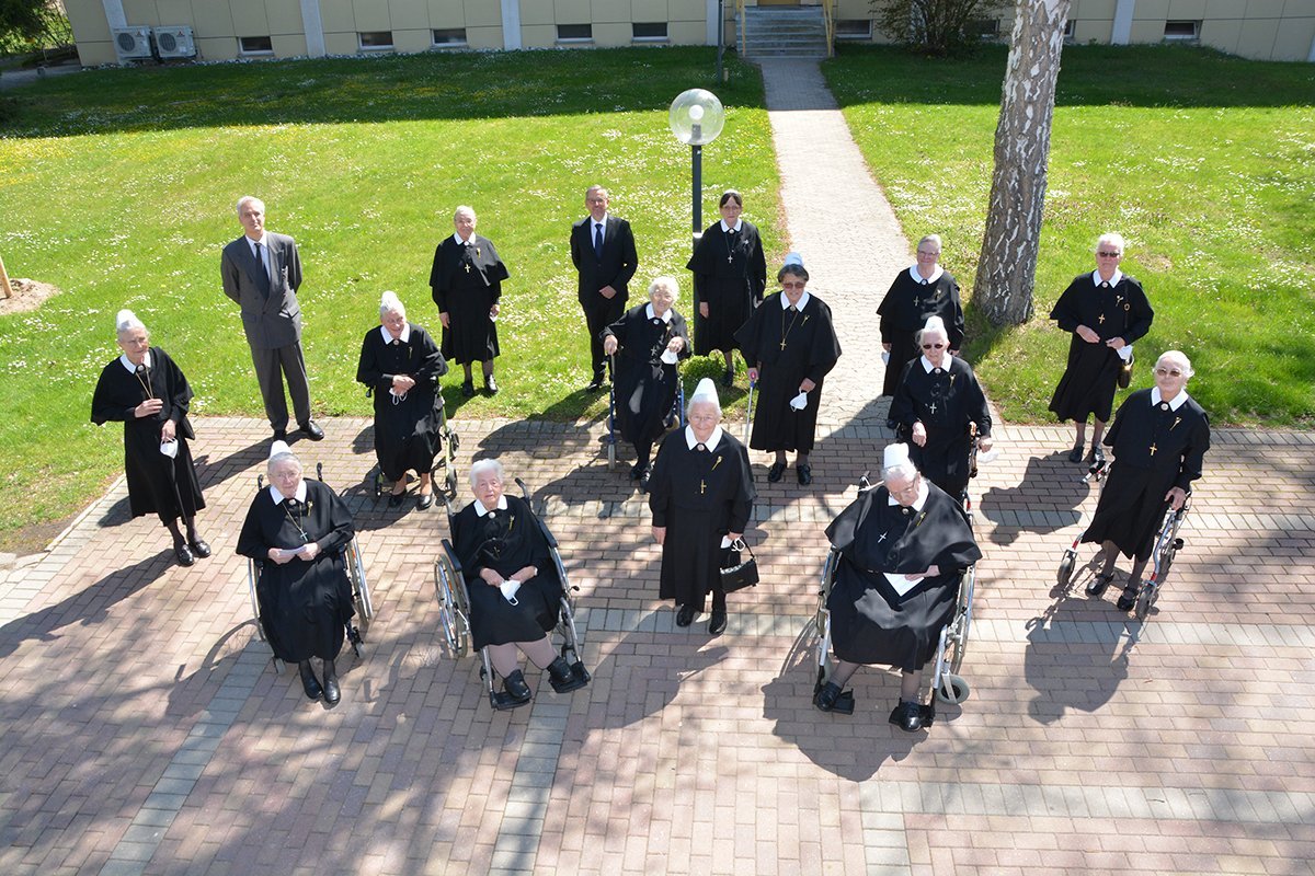 Gruppe von Nonnen in schwarzen Gewändern posiert im Freien auf einem Gehweg.