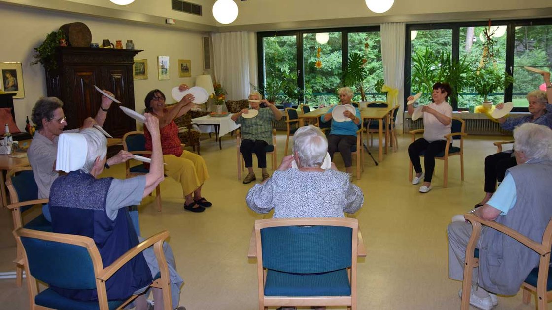 Senioren üben Gymnastik mit Papptellern im Seniorenzentrum Nürnberg.