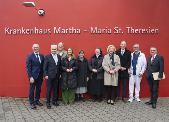 Gruppe von zehn Personen vor roter Wand mit Schriftzug Krankenhaus Martha-Maria St. Theresien.