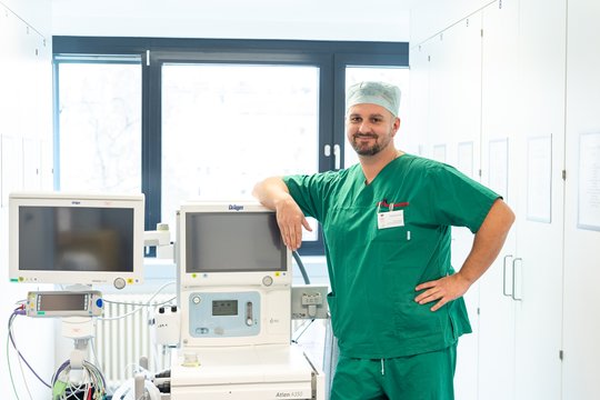 Anästhesietechnischer Assistent im Krankenhaus mit medizinischen Geräten im Hintergrund.