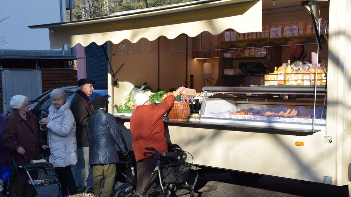 Senioren kaufen am mobilen Marktstand im Seniorenzentrum Nürnberg ein.