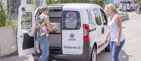 Mitarbeiter des Seniorenzentrum Martha-Maria Eckental beladen das Auto mit Essen auf Rädern