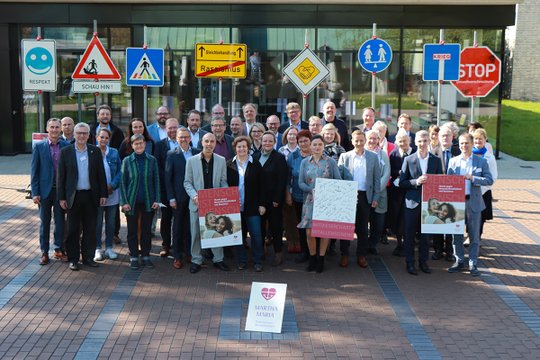 Gruppe von Menschen mit Plakaten gegen Rassismus vor modernen Gebäuden.