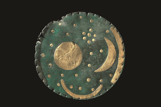 Bronzescheibe mit Sternen, Sonne und Mond auf dunklem Hintergrund.