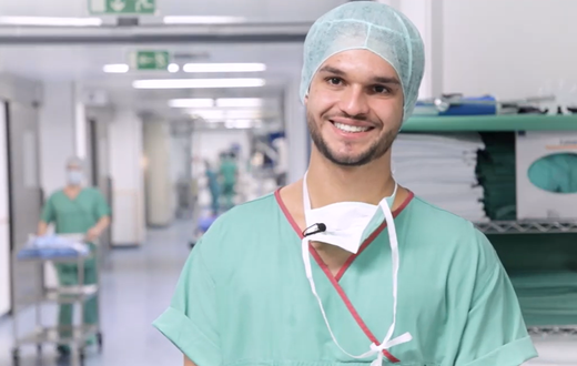 Lächelnder Chirurg in Krankenhausflur, bereit für Operation.