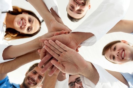 Mehrere Berufsgruppen legen die Hände aufeinanander.