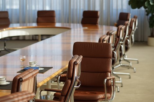 Großer Konferenztisch mit leeren Stühlen, bereit für Chefarztklausur 2025 in München.