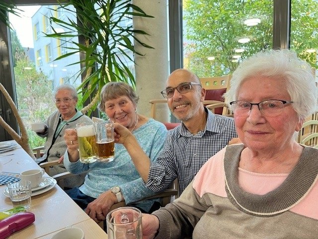 Senioren und Pfleger im Seniorenzentrum Eckental stoßen mit Bier an.