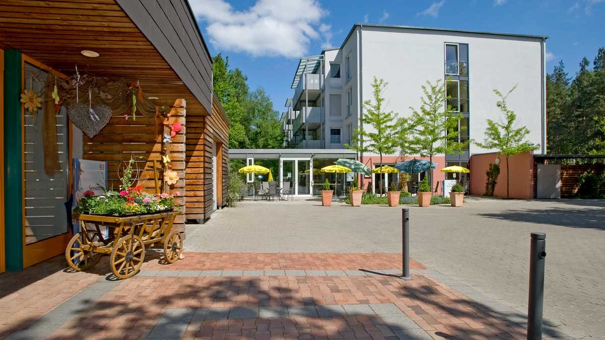 Eingangsbereich des Seniorenzentrums Nürnberg mit Blumen und Sonnenschirmen.