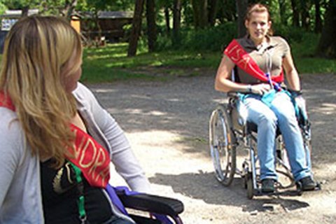 Zwei Personen im Rollstuhl im Freien bei einem Seminar.