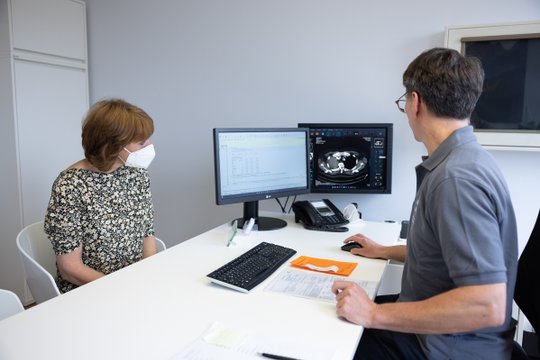 Patientin und Arzt besprechen CT-Bild der Lunge am Computerbildschirm.