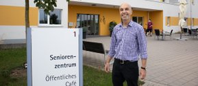 Einrichtungsleiter vor Seniorenzentrum Martha-Maria Eckental mit Eingang und Café-Schild.
