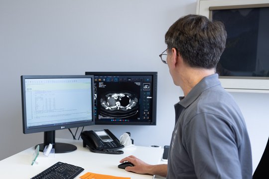 Patientin und Arzt besprechen CT-Bild der Lunge am Computerbildschirm.