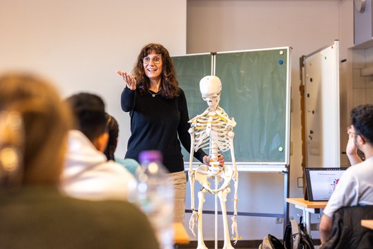 Lehrerin erklärt Skelettmodell vor Schülern in Pflegefachschule St. Theresien.