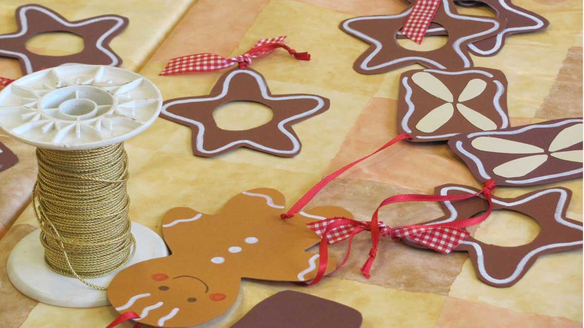 Weihnachtliche Bastelarbeiten mit Lebkuchenfiguren und goldener Schnur auf Tisch.
