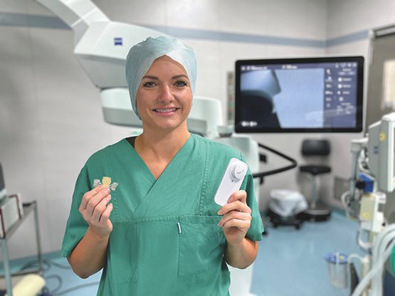 Chirurgin in OP-Kleidung hält medizinisches Gerät in Krankenhausumgebung.