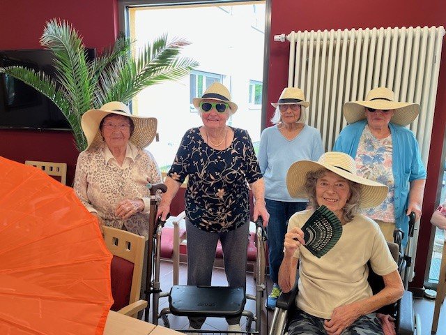 Seniorinnen im Seniorenzentrum Eckental mit Sommerhüten und Rollatoren, fröhliche Stimmung.