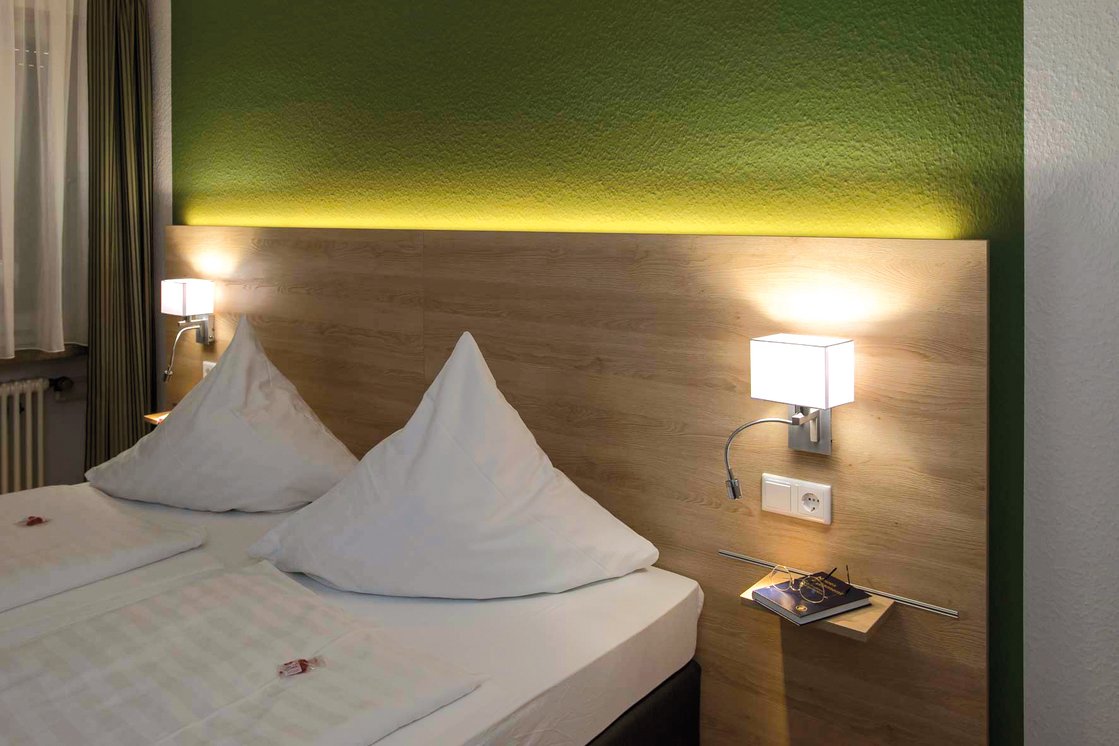 Modernes Doppelbett in Gästezimmer mit Holzverkleidung und Nachttisch.