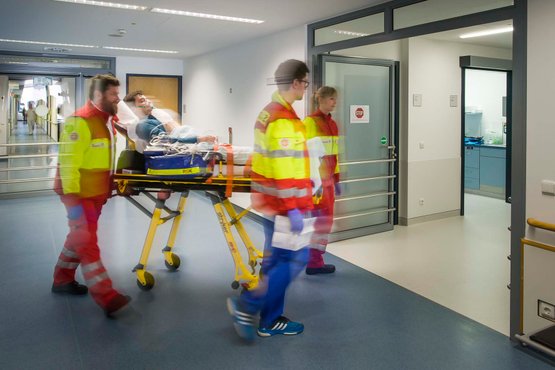 Sanitäter transportieren Patienten auf Trage in Krankenhausflur.