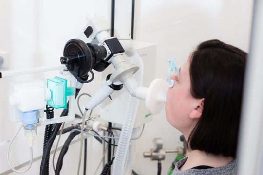 Frau bei Lungenfunktionstest mit medizinischem Gerät in einer Klinik.