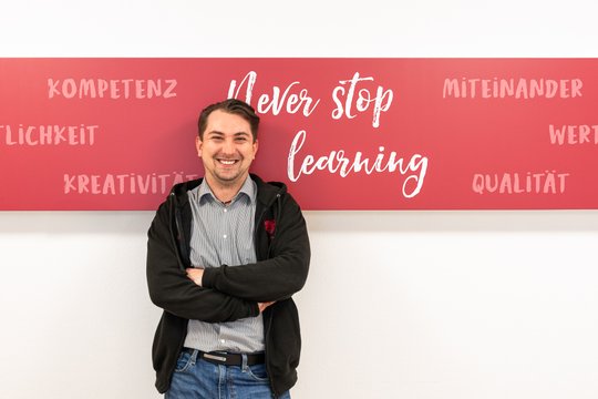 Franjo Bozic vor einer Wand im Seniorenzentrum Martha-Maria Stuttgart mit der Aufschrift Never Stop Learning