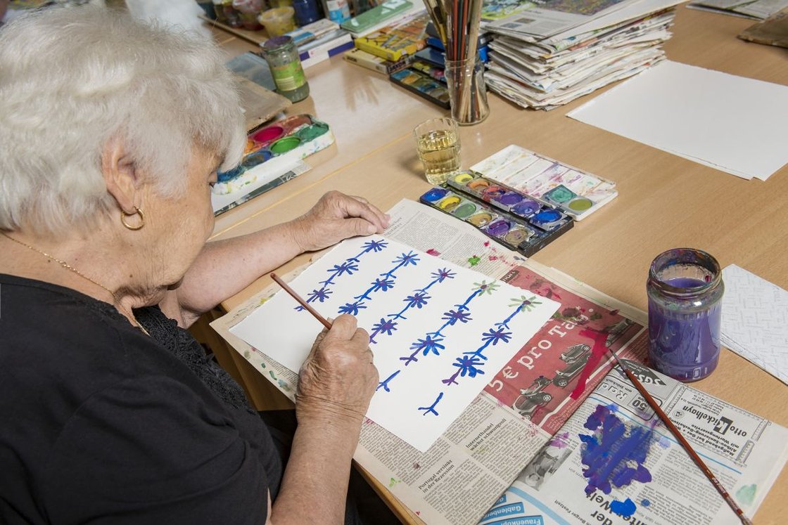 Seniorin malt mit Wasserfarben bei Maltherapie im Seniorenzentrum Stuttgart.