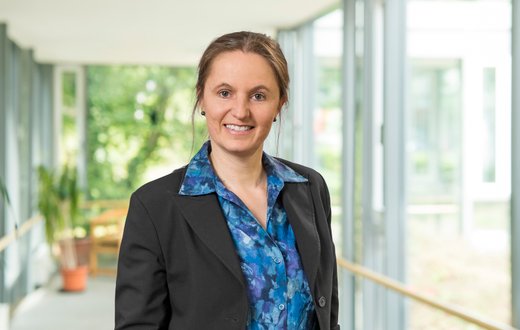 Frau in Geschäftskleidung in einem hellen, modernen Bürogebäude.