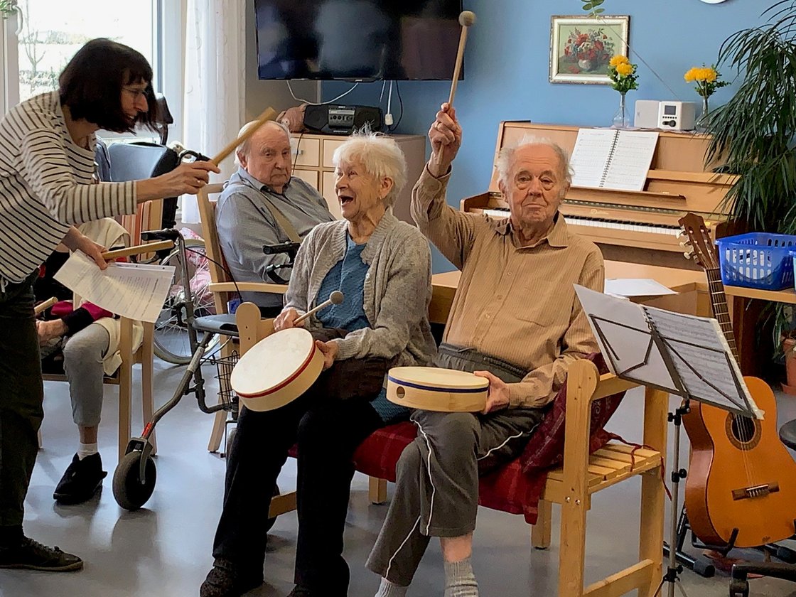 Senioren im Seniorenzentrum Eckental bei Musiktherapie mit Trommeln.