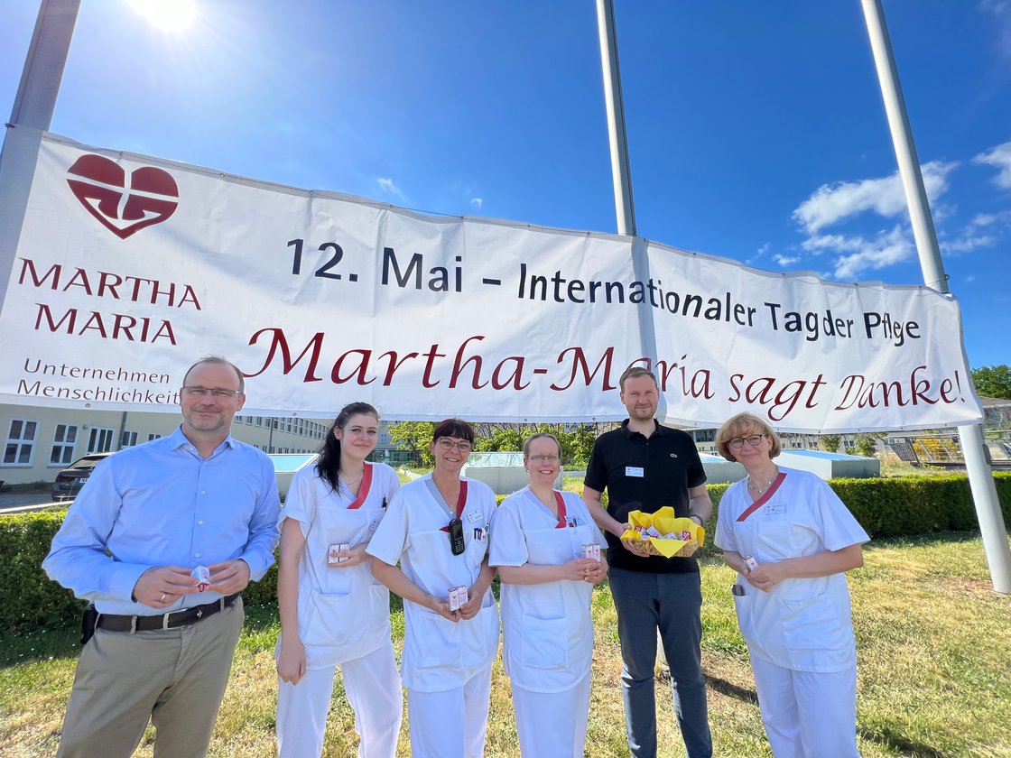 Gruppe vor Banner zum Internationalen Tag der Pflege bei Martha-Maria.