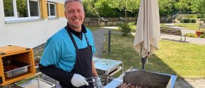 Mitarbeiter grillt Bratwürste im Garten des Seniorenzentrums Eckental.