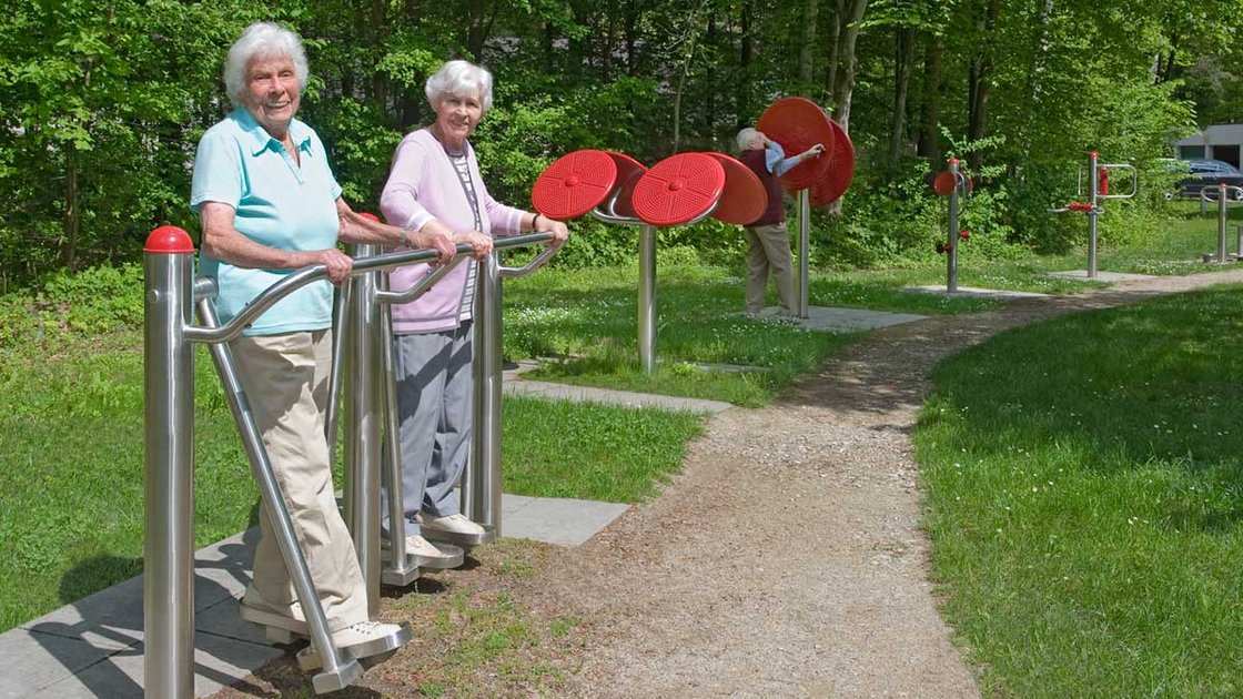 Seniorinnen trainieren an Fitnessgeräten im Garten des Seniorenzentrums Nürnberg.
