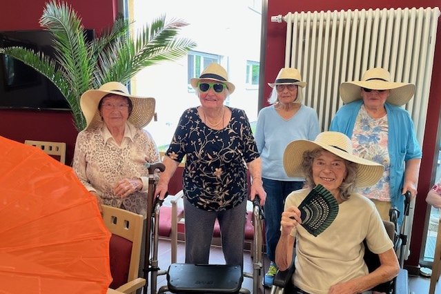 Seniorinnen im Seniorenzentrum Eckental mit Sommerhüten und Rollatoren, fröhliche Stimmung.