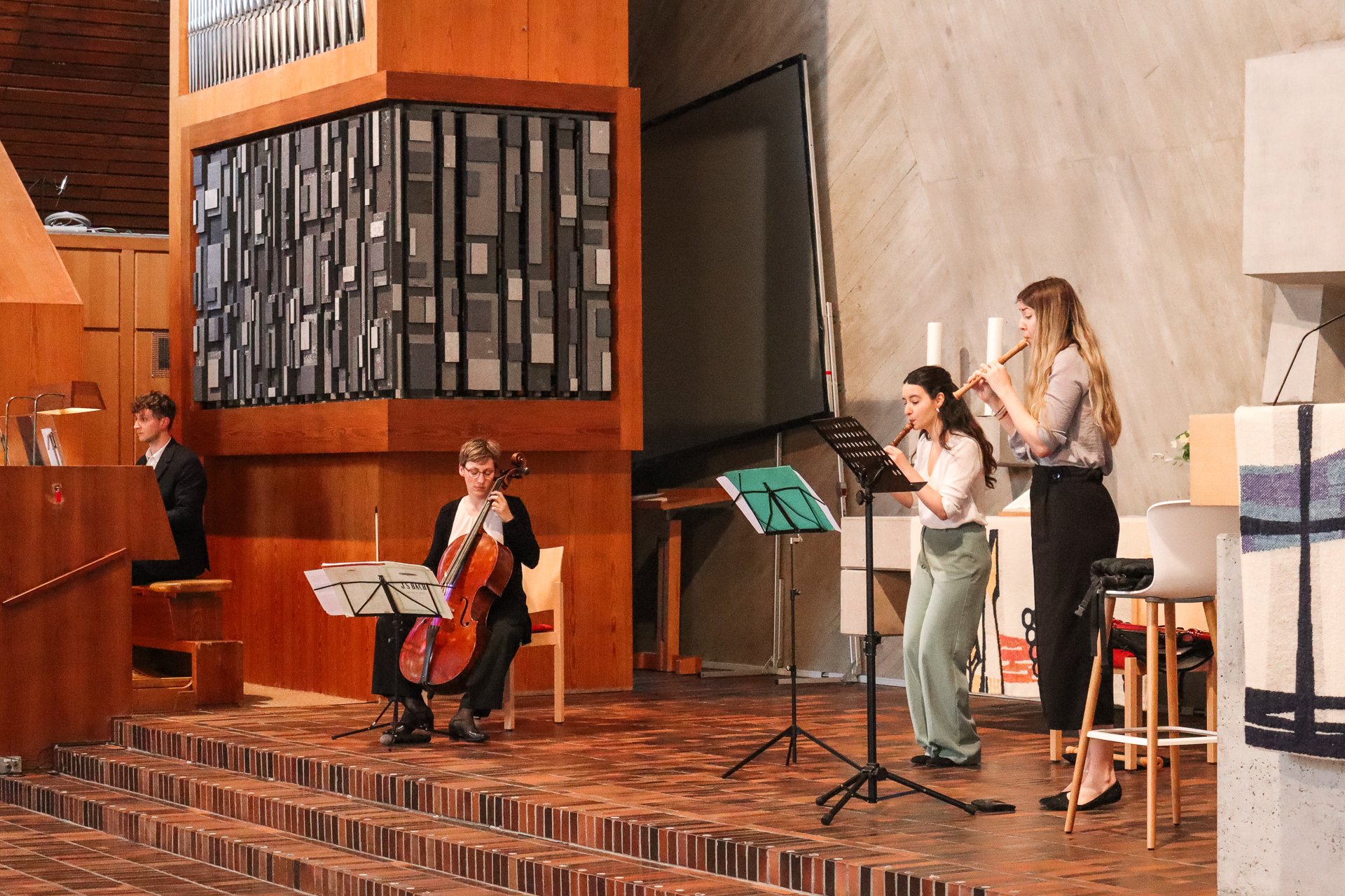 Vier Musiker spielen in einer Kirche, darunter ein Cello und Blockflöten.