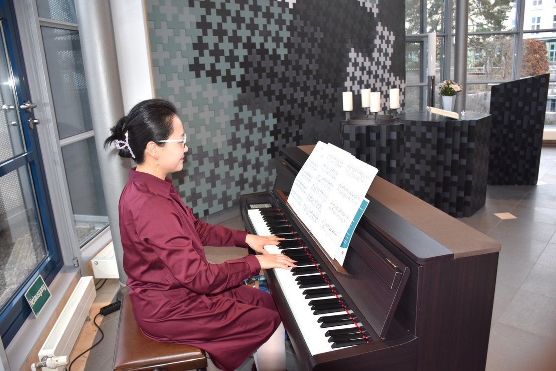 Frau spielt Klavier in modernem Raum mit gedämpftem Licht und Kerzen.
