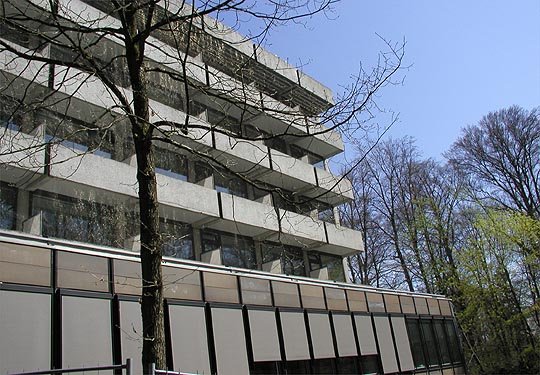 Modernes Krankenhausgebäude umgeben von Bäumen an einem sonnigen Tag.
