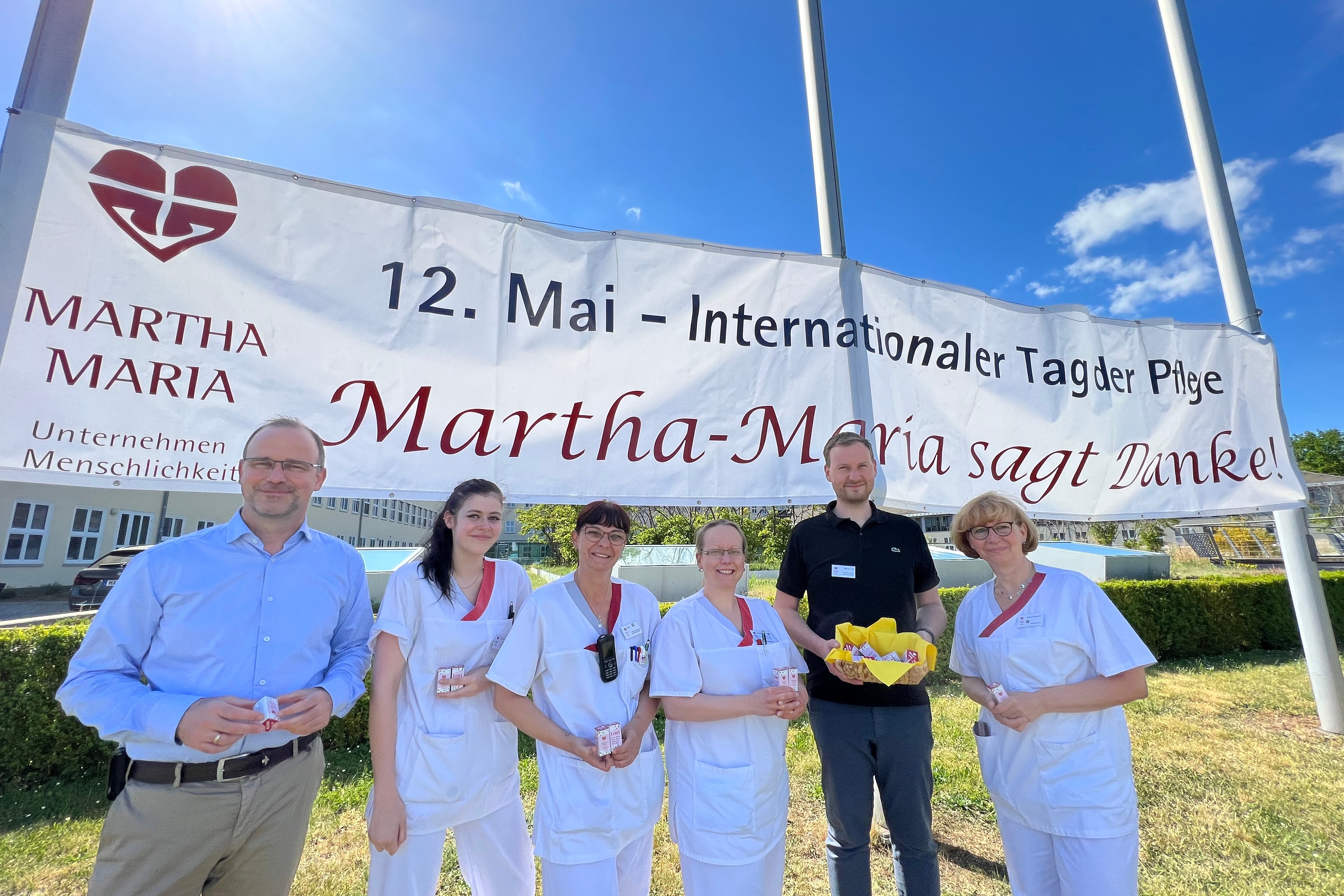 Gruppe vor Banner zum Internationalen Tag der Pflege bei Martha-Maria.