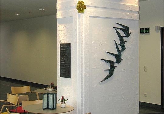 Kunstinstallation von fliegenden Vögeln in Krankenhauslobby mit Sitzbereich.