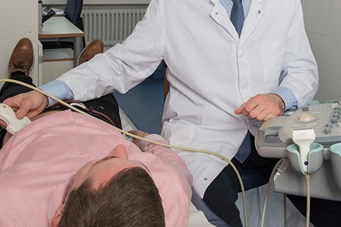 Arzt führt Ultraschalluntersuchung an liegendem Patienten im Krankenhaus durch.