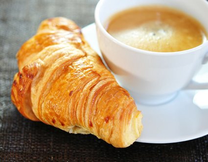 Frisches Croissant und Tasse Kaffee im Bistro des Krankenhauses München.
