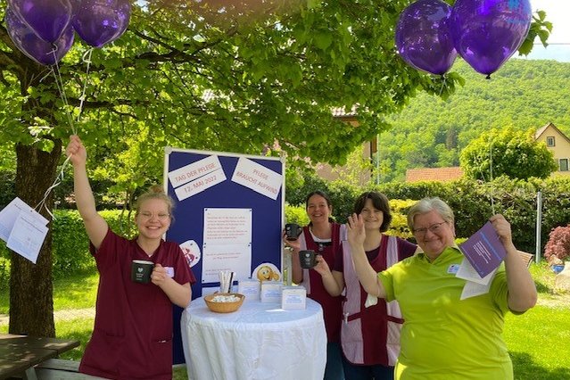 Pflegekräfte feiern den Tag der Pflege mit Ballons und Infotisch im Freien.