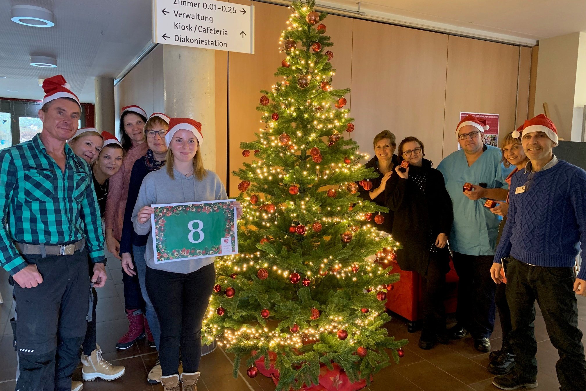 Mitarbeiter des Seniorenzentrums Eckental posieren mit Weihnachtsbaum und Nikolausmützen.