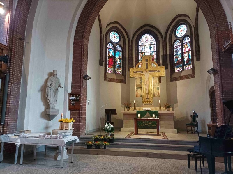 Kirchenaltar mit bunten Glasfenstern und Kerzen beleuchtet, festlich geschmückt.