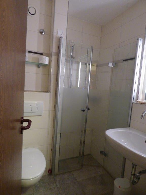 Kleines Krankenhausbad mit Dusche, Waschbecken und Toilette.